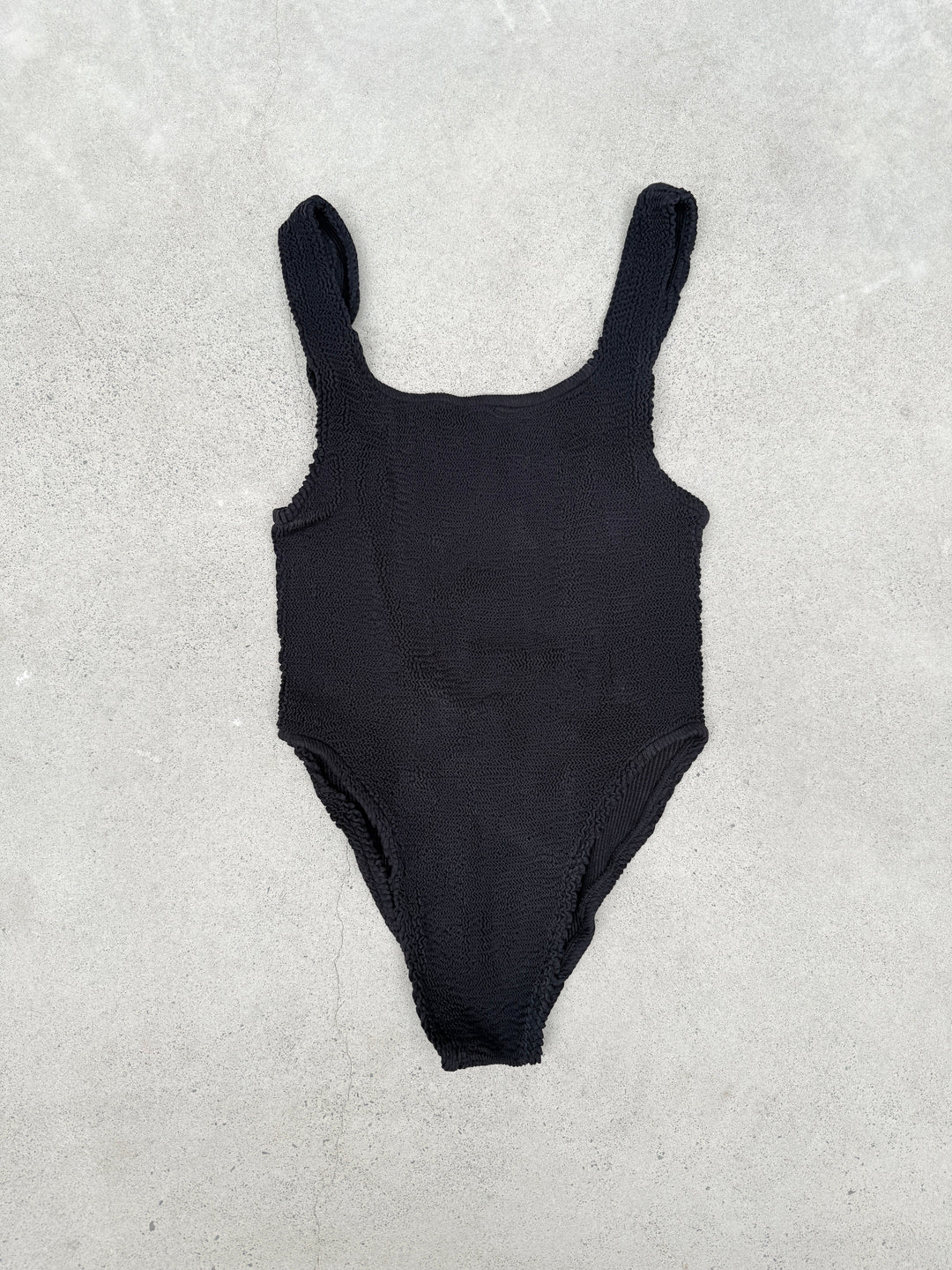 Black one-piece swimsuit with scooped back, suitable for sizes 6 to 16, designed for 80s-inspired surfing or swimming.