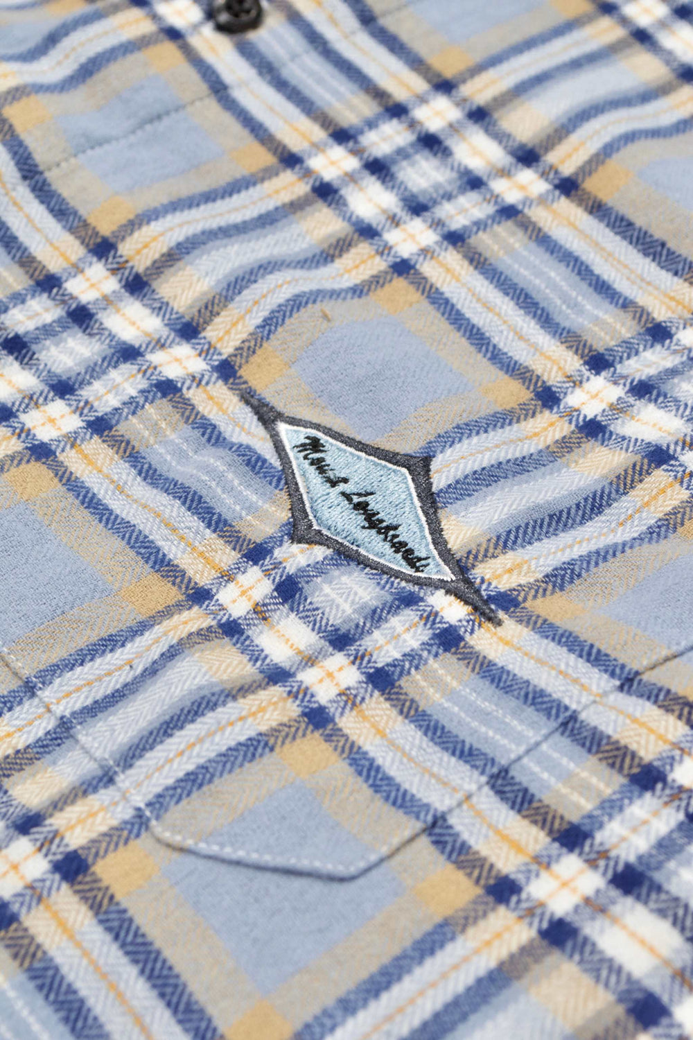 Blue plaid flannel shirt with embroidered diamond logo on pocket, featuring buttoned front and cuffs.