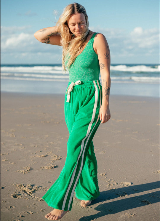 Woman wearing Atmosea Surf Pants in Apple Green on the beach.