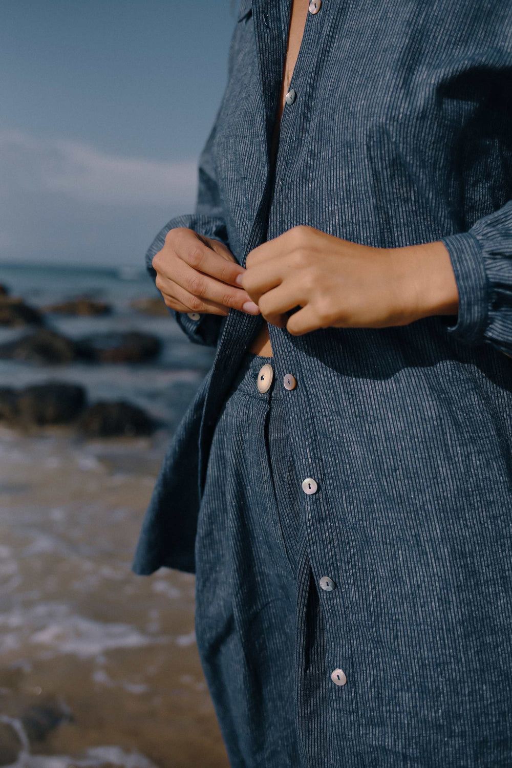 Navy pinstripe Yumi shirt with button-down front at the beach.