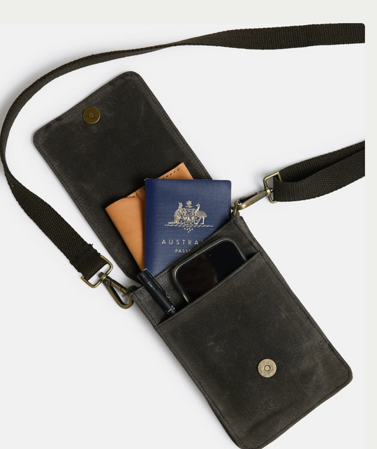 Slow Road Phone Satchel in black waxed canvas with strap, featuring compartments for phone and passport.
