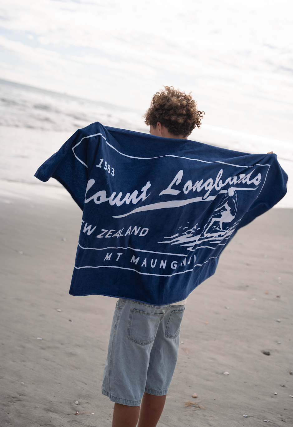 Retro Beach Towel in Navy held by person on beach.